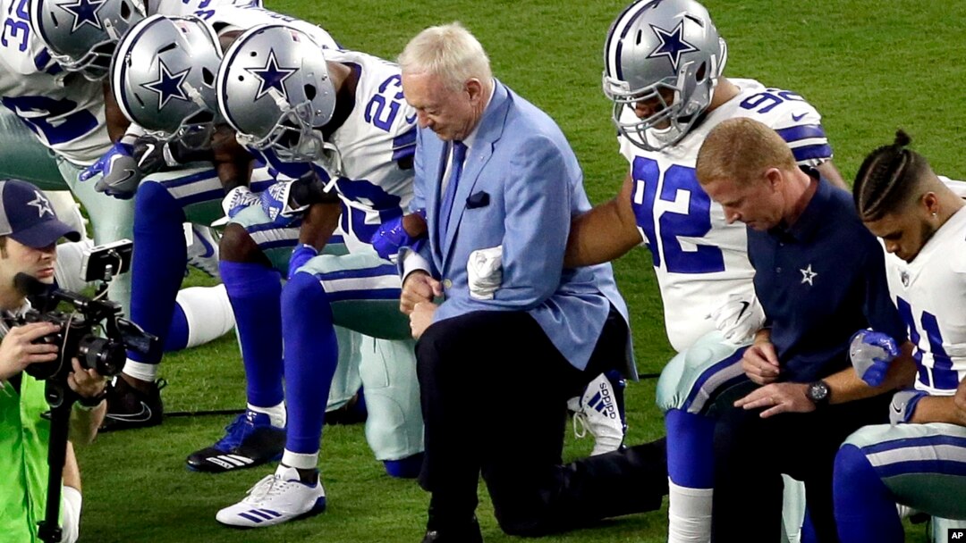 The Dallas Cowboys, led by owner Jerry Jones, center, take a knee during the national anthem prior to an NFL football game against the Arizona Cardinals, in Glendale, Arizona, Sept. 25, 2017.