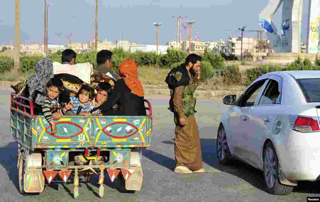A Free Syrian Army fighter mans a checkpoint, while children sit at the back of a pickup truck in Raqqa province, eastern Syria April 15, 2013.