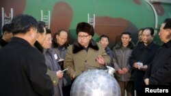 김정은 북한 국무위원장이 핵무기 연구 부문 과학자, 기술자들을 만나 핵무기 병기화 사업을 지도하는 모습. 사진 아래쪽에 핵탄두 기폭장치 추정 물체가 보인다.
