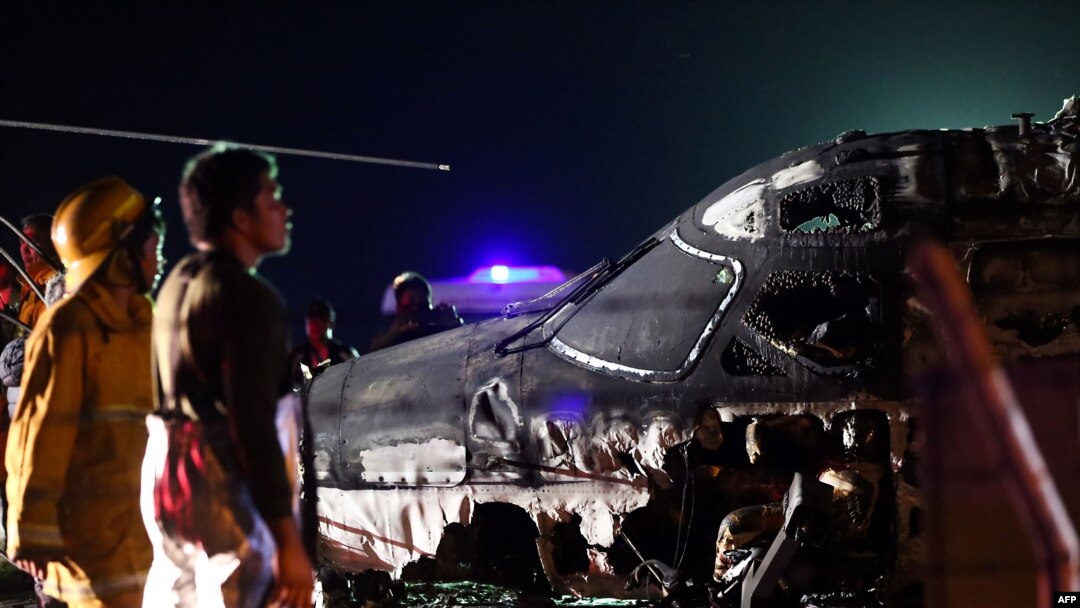 Rescuers stand next to the wreckage of a Westwind aircraft after it caught on fire during takeoff at Manila international airport in Manila on March 29, 2020. - A Japan-bound plane caught fire on takeoff at Manila airport in the Philippines late…