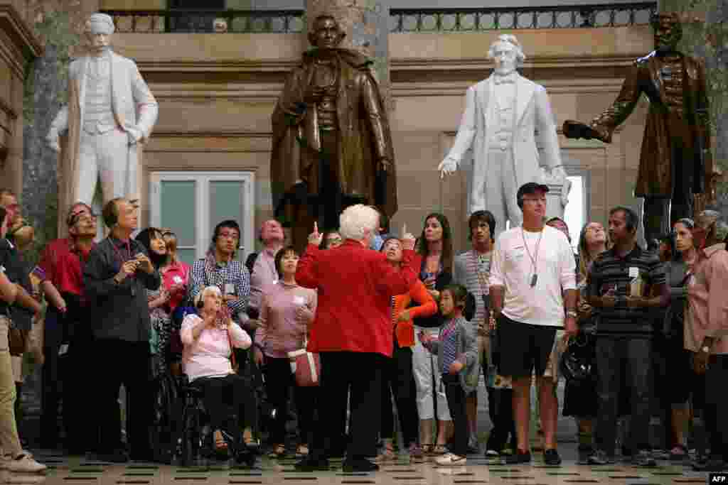 Seorang pemandu wisata (jaket merah) memberikan penjelasan kepada para turis yang mengunjungi Gedung Kongres AS atau Capitol Hill di Washington, DC. Wisata di gedung Kongres AS harus dihentikan akibat Kongres gagal menyepakati anggaran pemerintah federal.