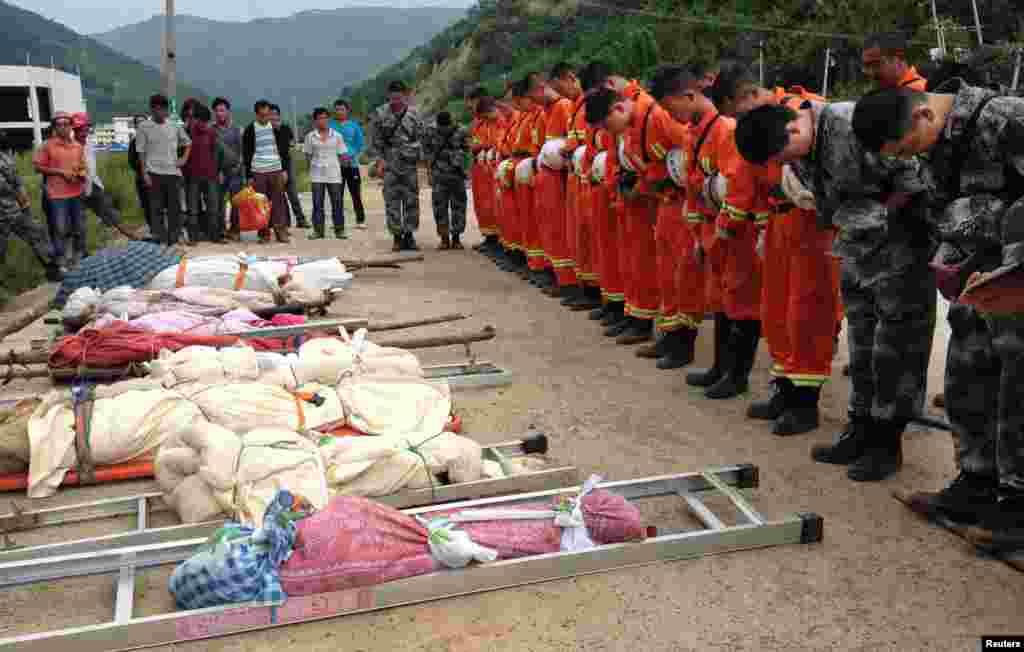 Rescuers bow to pay tribute to residents who were killed during an earthquake in Longtoushan township, Ludian county, Yunnan province, Aug. 4, 2014. 