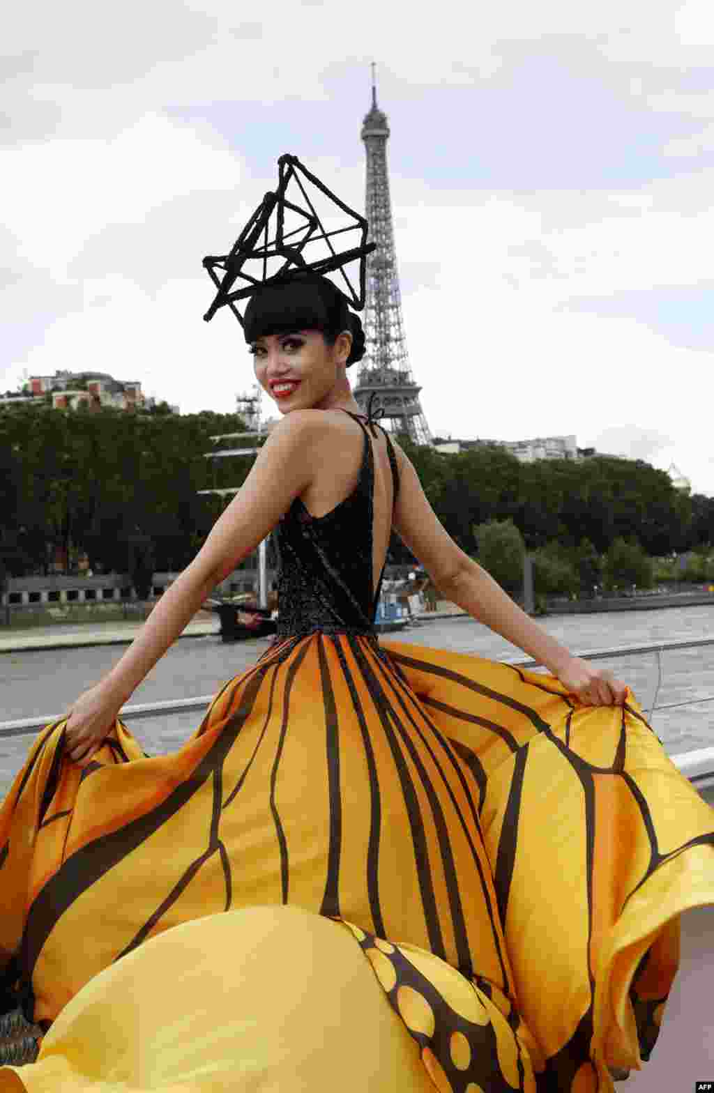 Model Vietnam, Jessica Minh Anh mengenakan kreasi musim gugur karyanya sendiri di kapal turis yang melintasi sungai Seine, dekat Menara Eiffel di Paris.