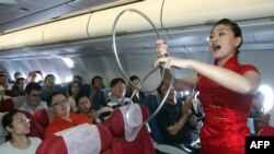 中國東方航空公司的空姐在客機上為乘客表演助興（2007年9月26日）。
