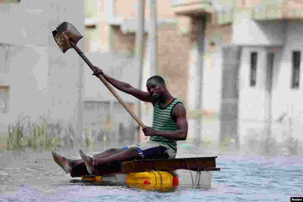 A resident uses a shovel to row through flooded streets after last week's heavy rains in Keur Massar, Senegal, Sept. 8, 2020.