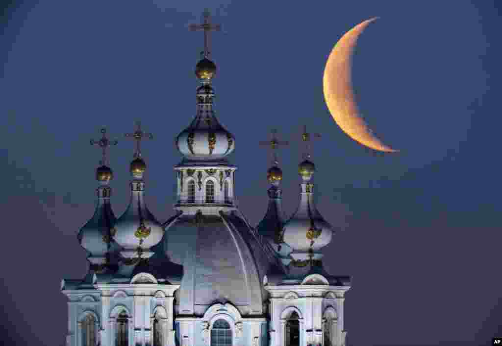 Bulan terbit di langit di atas kubah-kubah Katedral Smolny di St.Petersburg, Rusia. 