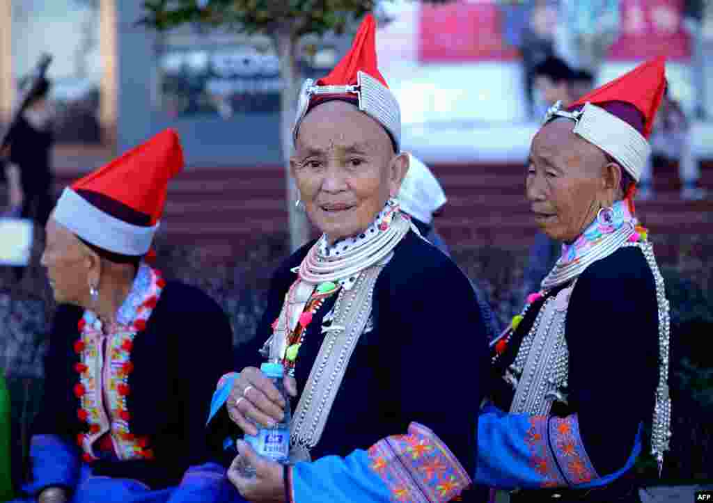 Tiga perempuan dari etnis minoritas China dengan pakaian tradisional mengunjungi kawasan bisnis di Beijing.