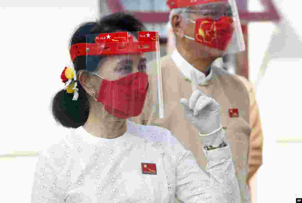 Myanmar leader Aung San Suu Kyi wearing a face shield, mask and gloves, gestures during a flag-raising ceremony to mark the first day of election campaign at the National League for Democracy party's temporary headquarters in Naypyitaw.