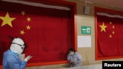 身穿防護服的醫護人員在武漢的一所方艙醫院里安慰一名病患。 （2020年2月27日）