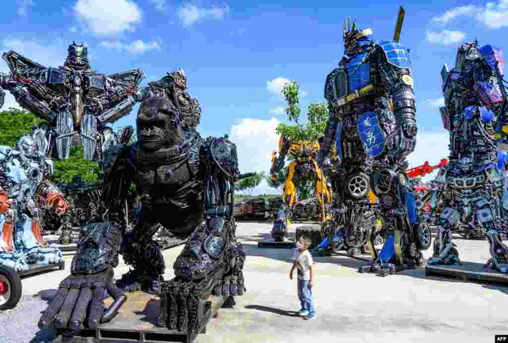 A child looks at a figure of King Kong in front of life-sized sculptures of characters from the "Transformers" film franchise, all made of scrap metal parts, at the Ban Hun Lek museum in Ang Thong, some 100km north of Bangkok, Thailand, July 18, 2020.