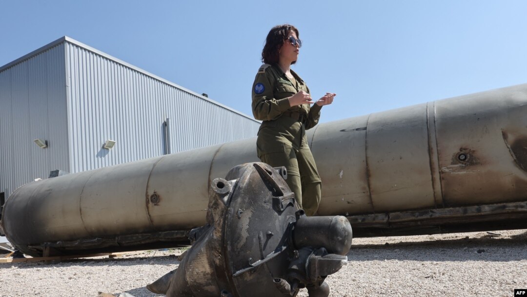 A member of the Israeli military stands next to an Iranian ballistic missile which fell in Israel on the weekend, during a media tour at the Julis military base near the southern Israeli city of Kiryat Malachi on April 16, 2024.