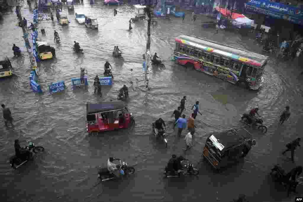 Commuters make their way along a flooded street after heavy monsoon rains in Pakistan's port city of Karachi, Pakistan.