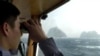 In this April 28, 2005, file photo, a South Korean coast guard looks at Dokdo islets, known as "Takeshima" in Japanese, through a telescope on the patrol ship Sambong-ho on the East Sea, South Korea. 