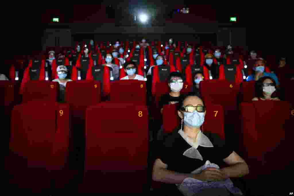 People wearing face masks to protect against the coronavirus sit spaced apart as they watch the film "Dolittle" at a movie theater in Beijing.