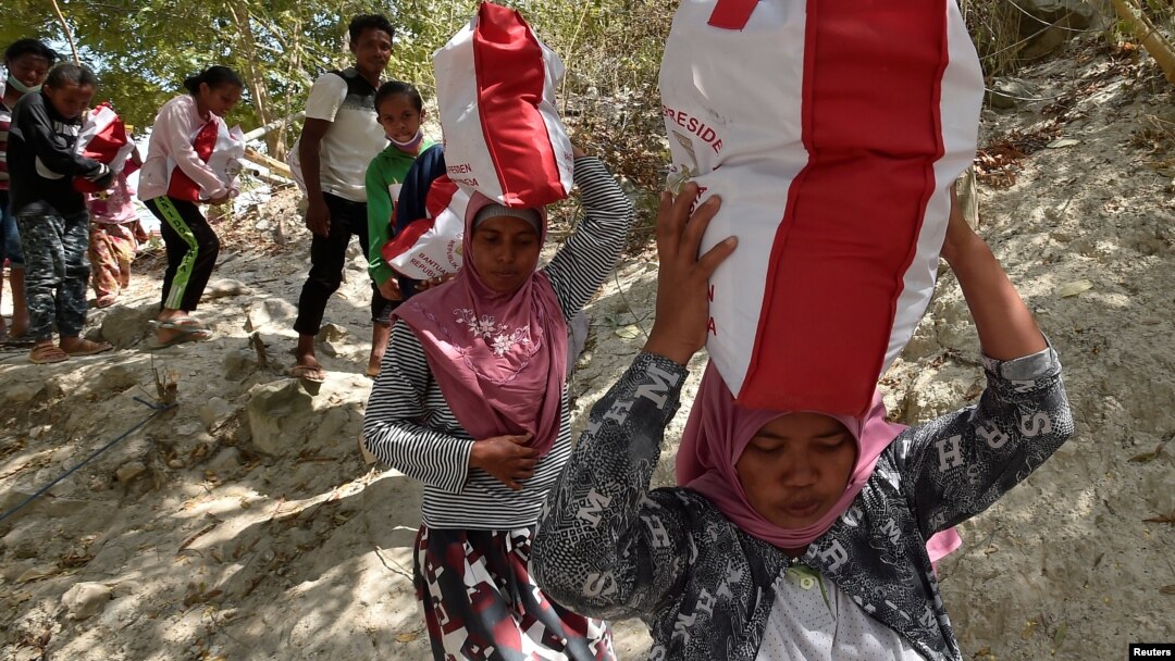 Residents affected by earthquake and tsunami carry aid provided during the visit of Indonesian President Joko Widodo in Donggala, north of Palu, Central Sulawesi, Indonesia, Oct. 3, 2018 in this photo taken by Antara Foto. 