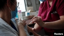 A member of the medical staff administers the Oxford-AstraZeneca COVID-19 vaccine to a colleague at the Foch hospital in Suresnes, near Paris, France, Feb. 8, 2021. 