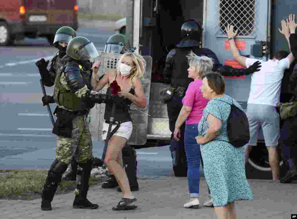 A woman fights with a police officer during a protest against the presidential election results as protesters encounter aggressive police tactics in the capital of Minsk, Belarus.