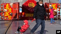 一名男子拉著一個孩子的推車走在北京前門的購物街上。（2023年1月17日）