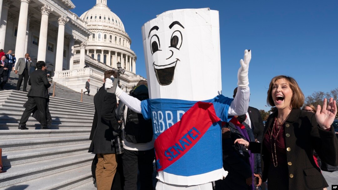 FILE - A man dressed as "Build Back Better Bill" wears a sash saying, "On to the Senate," Nov. 19, 2021, on Capitol Hill.