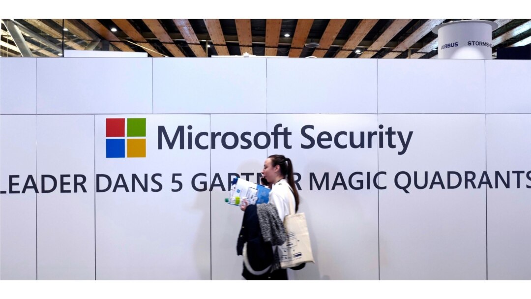 FILE - A woman walks in front of the Microsoft stand during the Cybersecurity Conference in Lille, northern France, Jan. 29, 2020.
