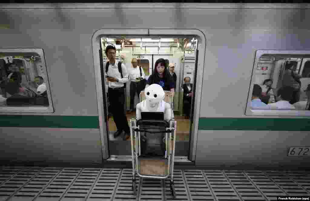 Tomomi Ota membawa kereta dorong yang berisi robot manusia 'Pepper' saat menaiki kereta bawah tanah di Tokyo, Jepang.