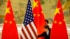 ARCHIVO - En esta fotografía de archivo del 14 de febrero de 2019, empleados chinos ajustan las banderas de Estados Unidos y China antes de la sesión inaugural de negociaciones comerciales entre representantes comerciales de Estados Unidos y China en Beijing. AP
