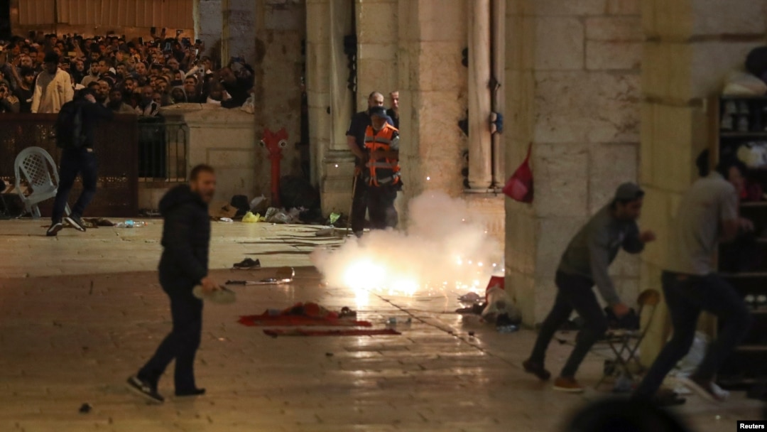 Wapalestina wakijihami kutokana na maguruneti ya polisi wa Israeli katika ghasia nje ya msikiti wa Al-Aqsa. 
