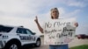Seorang warga bernama Mary Ann Foley membawa poster berisi seruan protes untuk pihak berwenang agar segera mengambil tindakan untuk menhentikan penembakan massal ketika ia mengunjungi acara mengenang korban penembakan di Allen, Texas, pada 7 Mei 2023. (Foto: AP/LM Otero)