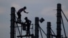 FILE - Workers on scaffolding are silhouetted at a construction site near Phnom Penh, Cambodia.