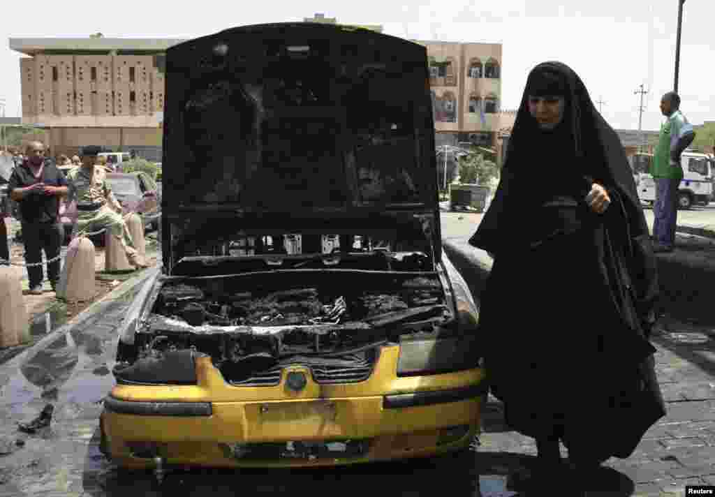 Phụ nữ Iraq đi ngang qua hiện trường một vụ đánh bom xe tại Sadr City, phía đông bắc thủ đô Baghdad, ngày 23/7/2012