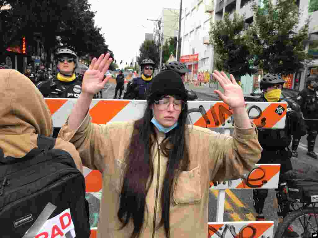 A protester stands with her hand up in front of a road blocked by Seattle police in the Capitol Hill Organized Protest zone, Washington. Police in Seattle have torn down demonstrators' tents in the city's so-called occupied protest zone after the mayor ordered to clear it.