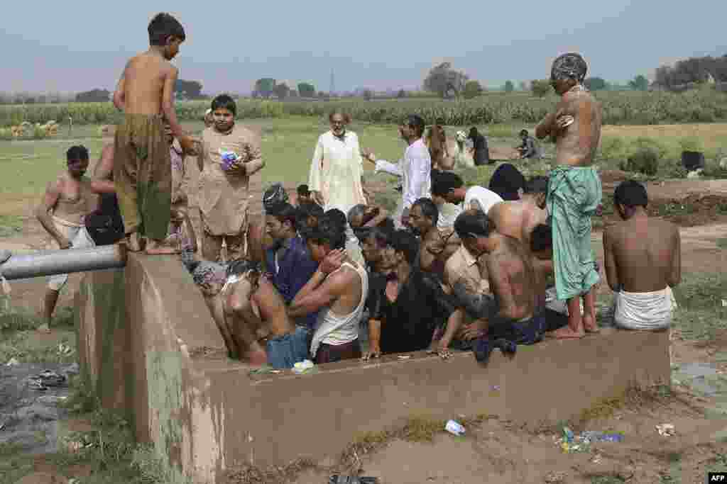 Farmers and vendors take bath at a cattle market set to buy sacrificial animals ahead of Eid al-Adha Muslim festival or the 'Festival of sacrifice' in Lahore, Pakistan.