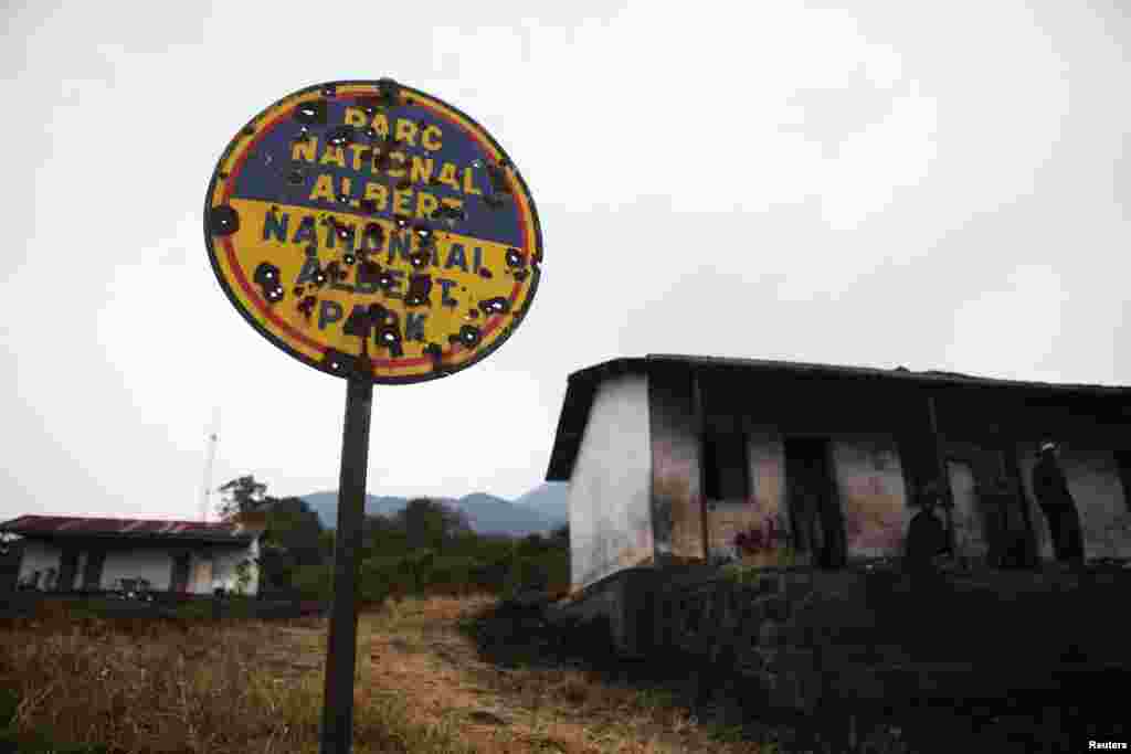 Luxury tourist quarters built during the rule of Mobutu Sese Seko that were destroyed and abandoned in earlier violence now serve as housing for some militias. The park's bullet-riddled welcome sign indicates the park's former name.