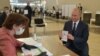 Russian President Vladimir Putin shows his passport to a member of a local electoral commission as he arrives to cast his ballot in a nationwide vote on constitutional reforms at a polling station in Moscow, July 1, 2020. 