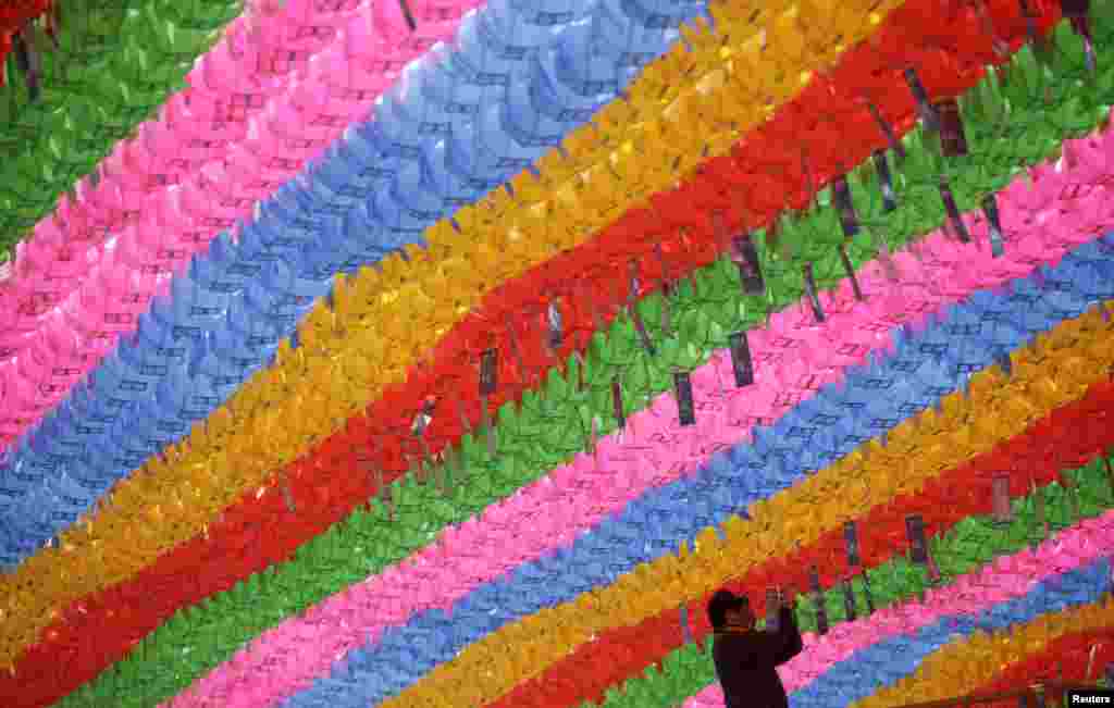 Seorang pekerja melampirkan kartu doa dan harapan yang berisi nama-nama pada lentera teratai dalam rangka persiapan hari kelahiran Sang Budha di Kuil Jogye di Seoul. Kelahiran Budha diperingati pada tanggal 6 Mei di Korea Selatan. 