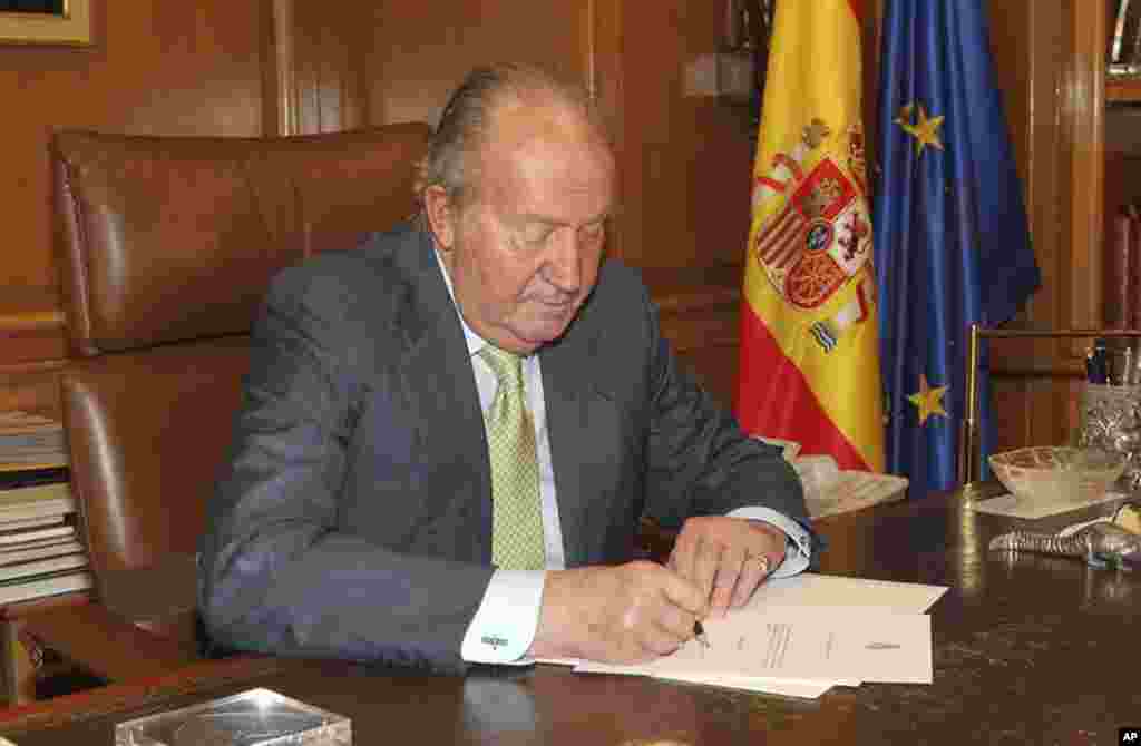 Nesta foto, cortesia do Palácio Real, o Rei Juan Carlos assina o documento que abre o seu caminho para a abdicação do trono. Palácio de Zarzuela, Junho 2, 2014.