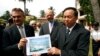 Cambodian official Han Touch (r) and German Embassy officer Adelbert Eberhardt hold a design of a memorial building as Joachim Baron Von Marschall, center, German Ambassador to Cambodia, watches at the building site, at the Tuol Sleng Genocide Museum, in in Phnom Penh, Cambodia, July 10, 2014. 