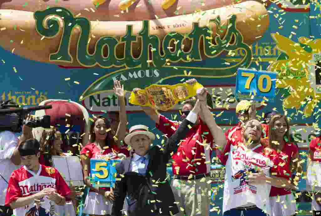 Joey Chestnut, right, is declared the men's competition winner of Nathan's Famous Fourth of July International Hot Dog Eating Contest, in New York.