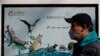 FILE - A man wearing a protective face mask walks by a propaganda poster promoting to protect wildlife after authorities crackdowns on wild animal markets following the coronavirus outbreak in Beijing, March 11, 2020. 