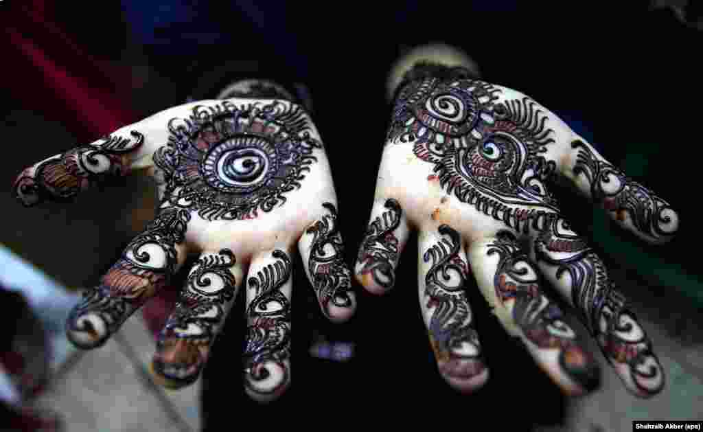 Seorang perempuan muslim menunjukkan hiasan tattoo Henna yang dibiarkan mengering sebelum perayaan hari raya Idul Fitri di Karachi, Pakistan.