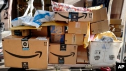 FILE - Amazon Prime boxes are loaded on a cart for delivery in New York City, Oct. 10, 2018. Online retail sales have surged during the coronavirus pandemic.
