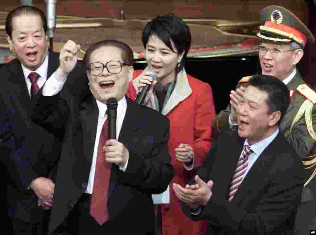 2000年12月20日,在澳门回归中国纪念仪式上,中国主席江泽民和副总理钱其琛(左)、解放军总政治部主任于永波(右后)、澳门特首何厚铧(右)等人同台唱歌。美联社的图片说明没说图上的女士是谁,貌似澳门赌王何鸿燊的四姨太梁安琪。