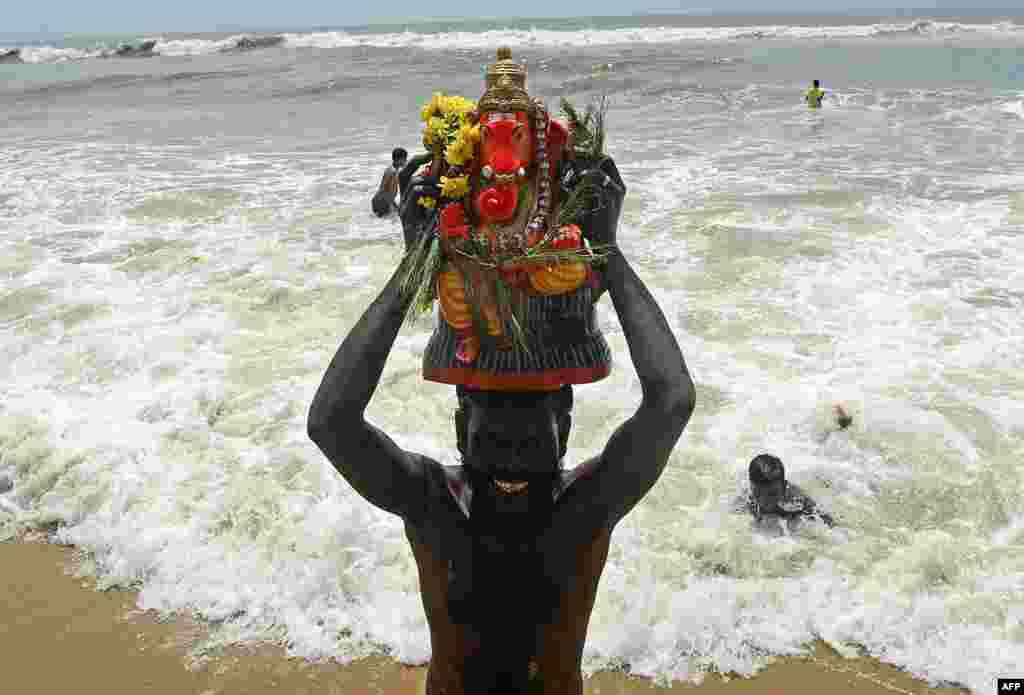 A volunteer carries a clay idol of Hindu elephant-headed deity Ganesh for immersion on the third day of the Ganesh Chaturthi festival, in Chennai, India.