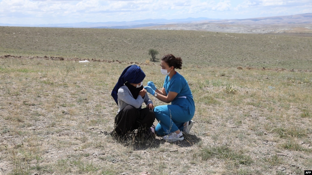 A health worker traveled hundreds of kilometers on July 8, 2021 to get things done. She gave COVID-19 shots to farmworkers in the village of Oguzlar in Turkey. (Photo by Adem ALTAN / AFP)