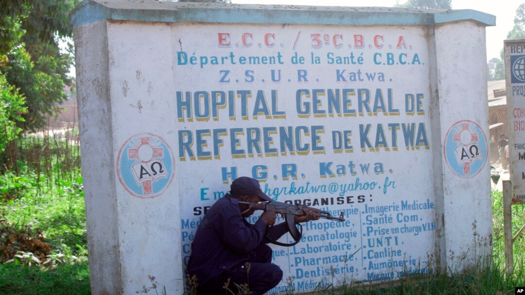 FILE - Police shelter behind a hospital sign as they guard a hospital in Butembo, Congo, April 20, 2019, after militia members attacked an Ebola treatment center in the city’s Katwa district overnight.