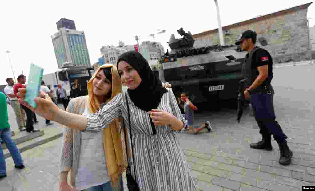 Turis-turis Aljazair mengambil swafoto di depan tank yang terbengkalai setelah kudeta yang digagalkan, di Lapangan Taksim di Istanbul, Turki (17/7). (Reuters/Murad Sezer)