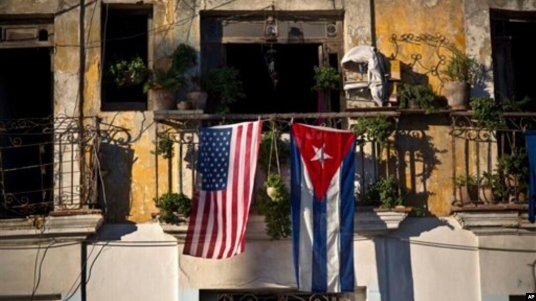 FILE - U.S. and Cuban flags hang from a balcony in Old Havana, Cuba, Dec. 19, 2014.